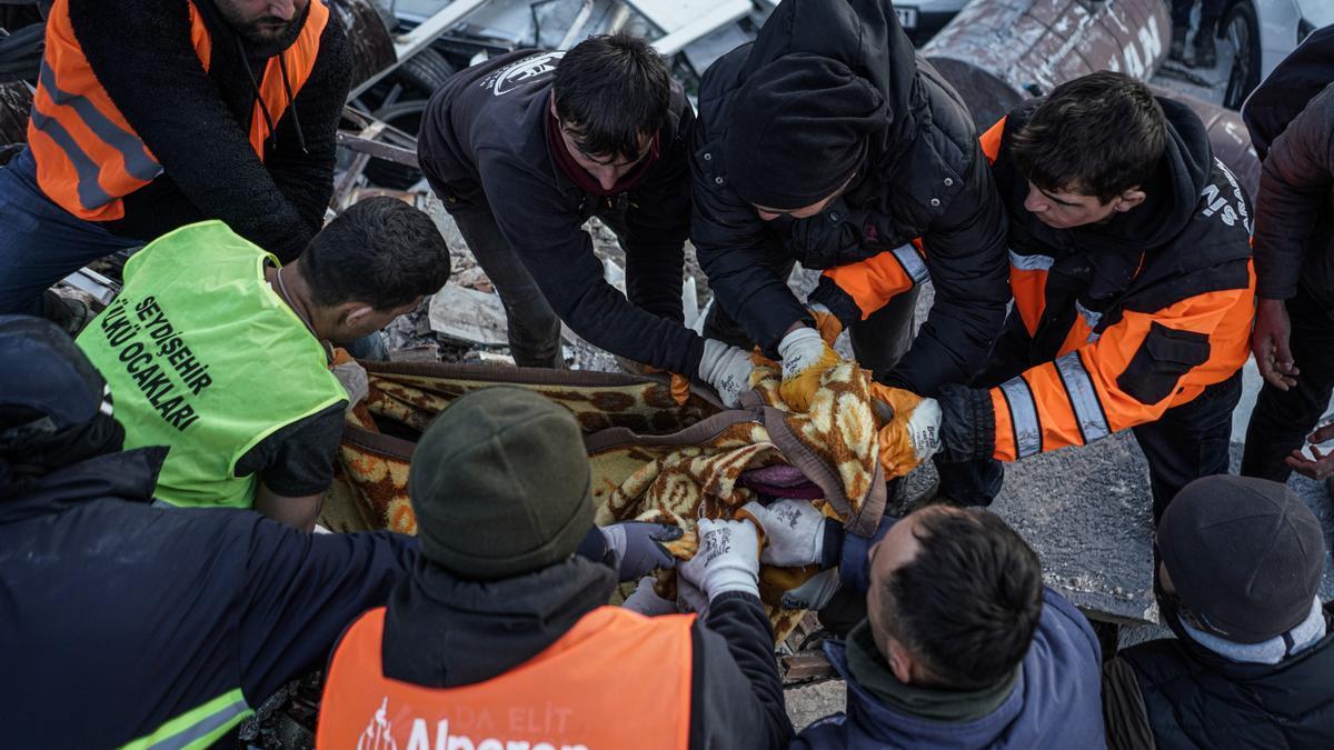 Un equipo de rescate cubre con una manta un cuerpo hallado bajo los escombros de un edificio en Antakya, Turquía.
