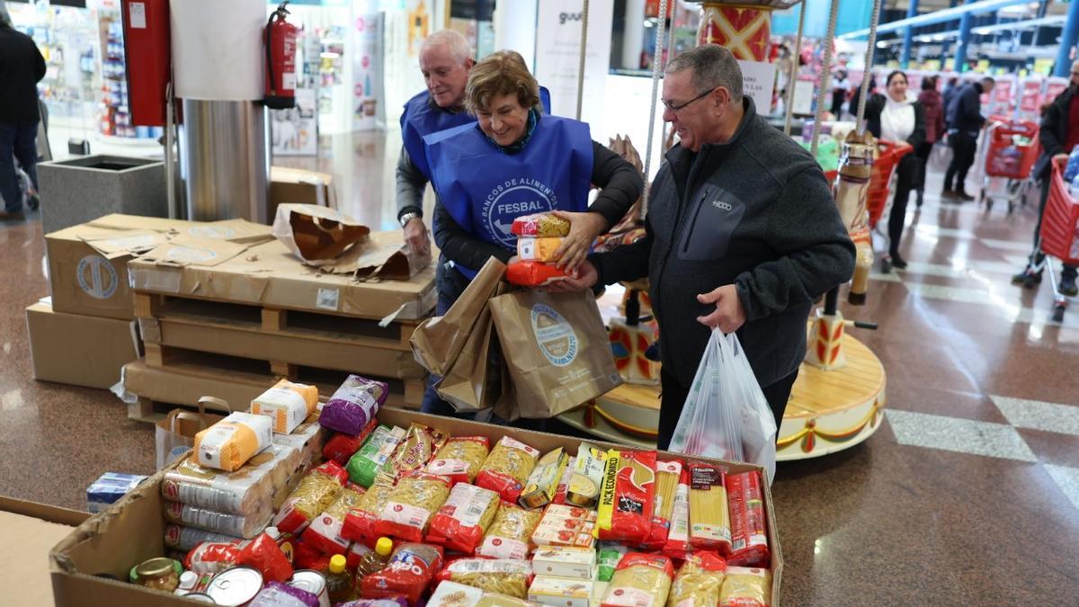 Inmaculada Mitxitorena y F&eacute;lix Irigoyen (voluntarios) colocan productos que ofrece un cliente en el Hipermercado Eroski.