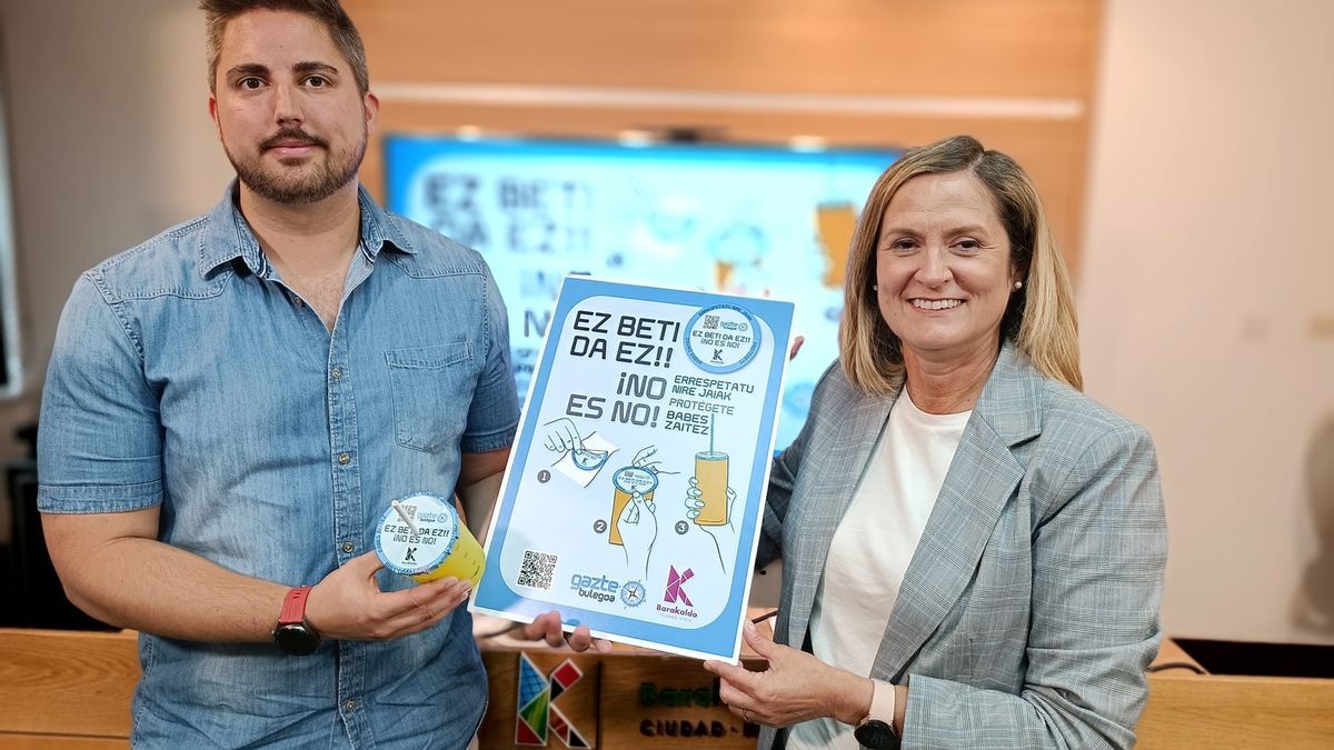 Jonathan Mart&iacute;n y Amaia del Campo posan con un cubrevasos y el cartel de la campa&ntilde;a.