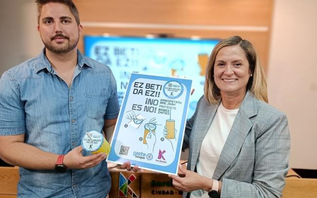 Jonathan Mart&iacute;n y Amaia del Campo posan con un cubrevasos y el cartel de la campa&ntilde;a.