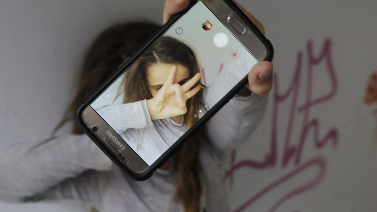 Una niña se hace un selfi con su teléfono móvil mientras los expertos piden que se racione la cantidad y los momentos del uso del mismo