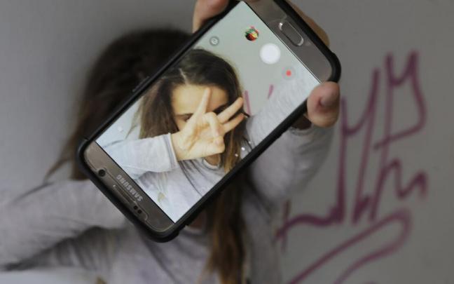 Una niña se hace un selfi con su teléfono móvil mientras los expertos piden que se racione la cantidad y los momentos del uso del mismo Una niña se hace un selfi con su teléfono móvil mientras los expertos piden que se racione la cantidad y los momentos del uso del mismo
