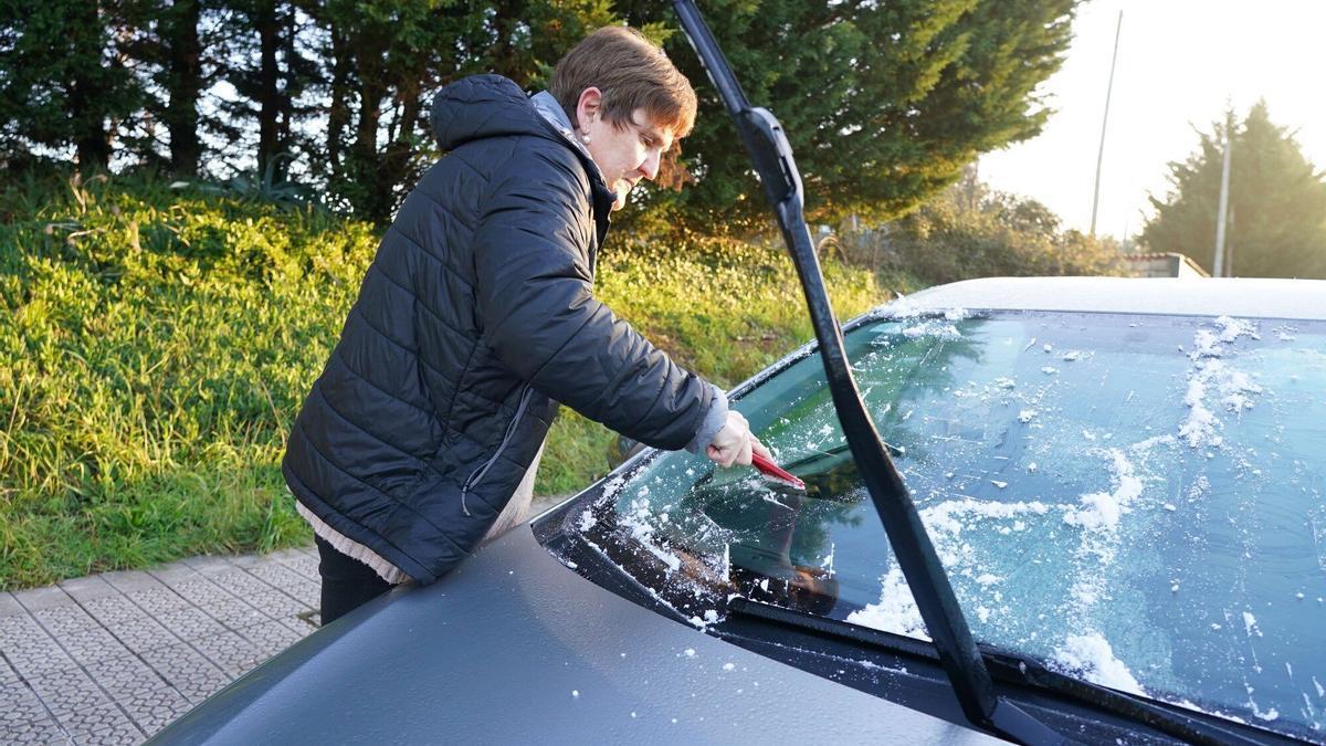 Una mujer retira el hielo acumulado en el parabrisas de su coche