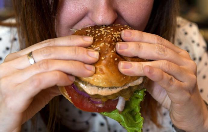 Una mujer muerde una hamburguesa