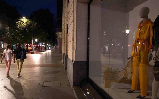 Varias personas caminan por la Gran V&iacute;a de Bilbao con las luces de los comercios apagadas