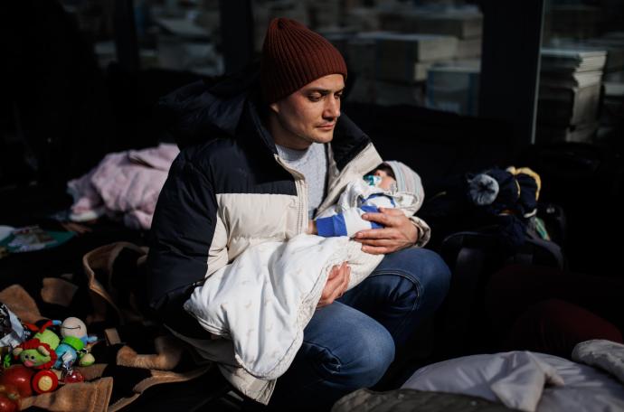 Una hombre sostiene un bebé, en un centro comercial habilitado para los refugiados, en Mylny, (Polonia).