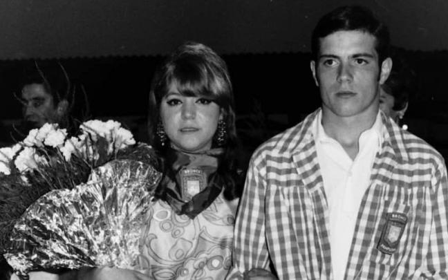 Una madrina, vestida ‘de gala’, junto a un mozo en un acto institucional.