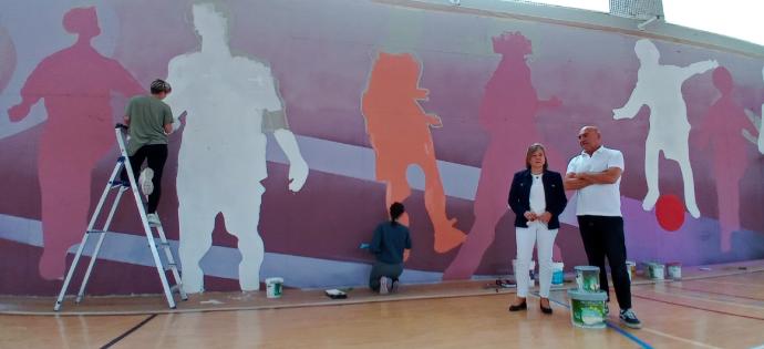 La alcaldesa, Anabel Landa, y el artista Jorge López de Guereñu, junto al mural ubicado en el interior del kirolgune de Berango.