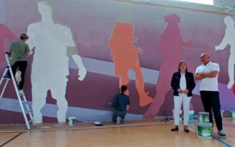 La alcaldesa, Anabel Landa, y el artista Jorge López de Guereñu, junto al mural ubicado en el interior del kirolgune de Berango.