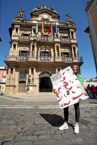 La joven pamplonesa Olaia Merino Erviti posa con el cartel de Sanfermines 2022 en la plaza Consistorial minutos antes de las 12 del mediodía.