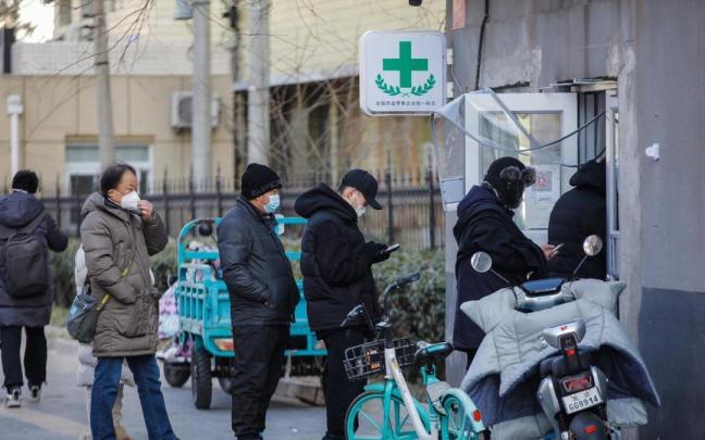 Varias personas hacen cola para comprar medicinas en una farmacia de Pekín.