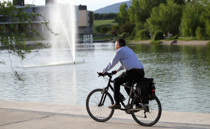 Un hombre pasea en bicicleta junto al lago de Sarriguren.