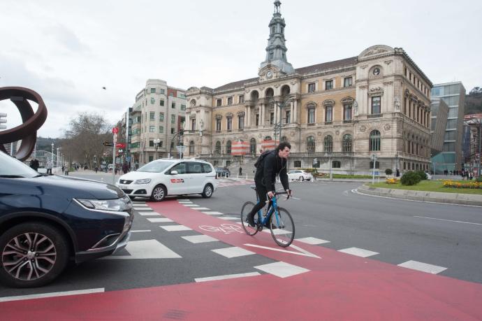 Un hombre pasa cerca del Ayuntamiento de Bibao en bicicleta