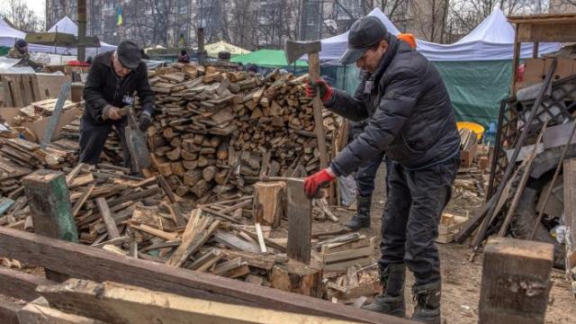 Dos hombres ucranianos cortan madera en Kiev en uno de los campamentos improvisados.