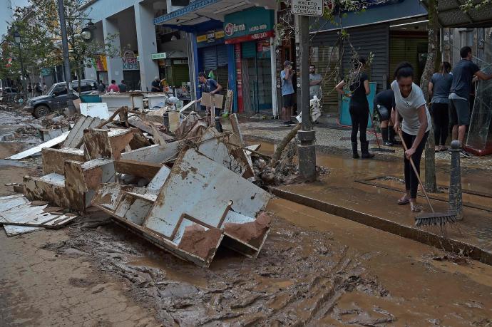 Varias personas limpian los destrozos causados por las inundaciones.