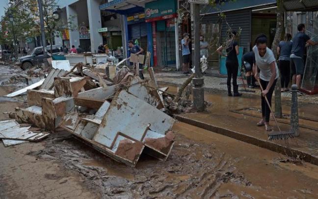 Varias personas limpian los destrozos causados por las inundaciones.