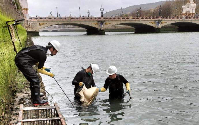 Un grupo de operarios retira un inodoro del cauce del Urumea en Donostia