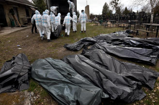 Varios trabajadores trasladan a la morgue los cuerpos exhumados de una fosa común en Bucha.