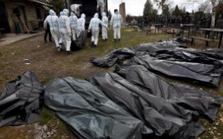 Varios trabajadores trasladan a la morgue los cuerpos exhumados de una fosa común en Bucha.