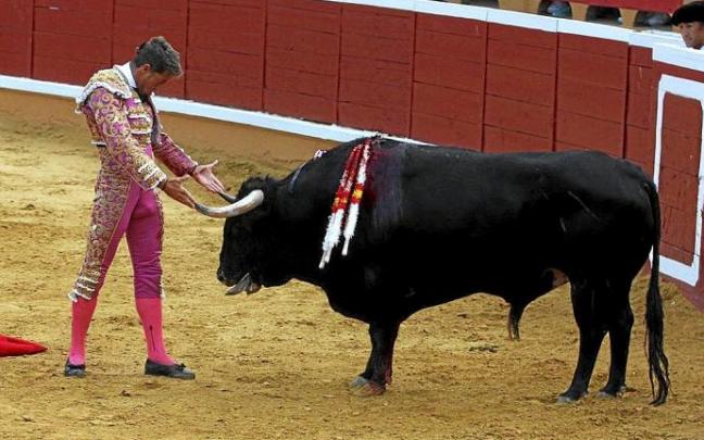 Escribano se desplanta posando sus manos en los pitones del segundo toro, 'Ventolín'.