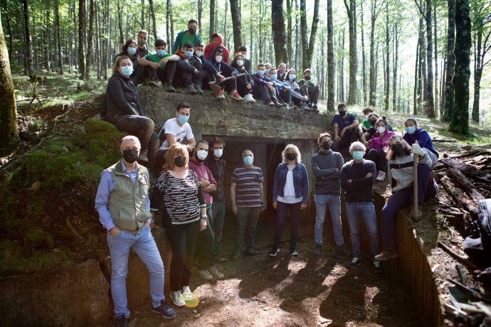 Los y las representantes del Gobierno de Navarra Martin Zabalza, la consejera Ana Ollo, Carlos Amatriain y José Mª Gastón, acompañados por Maite Errea, concejante de Eugi , y por responsables y participantes en el campo, en la entrada de uno de los búnker