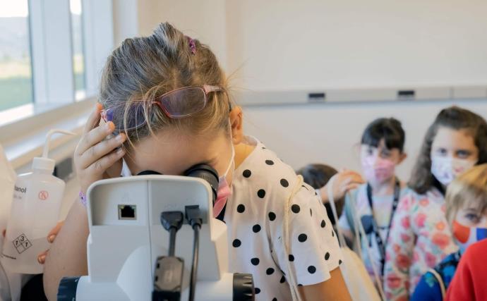 Una de las niña observa por el microscopio en uno de los talleres realizados.