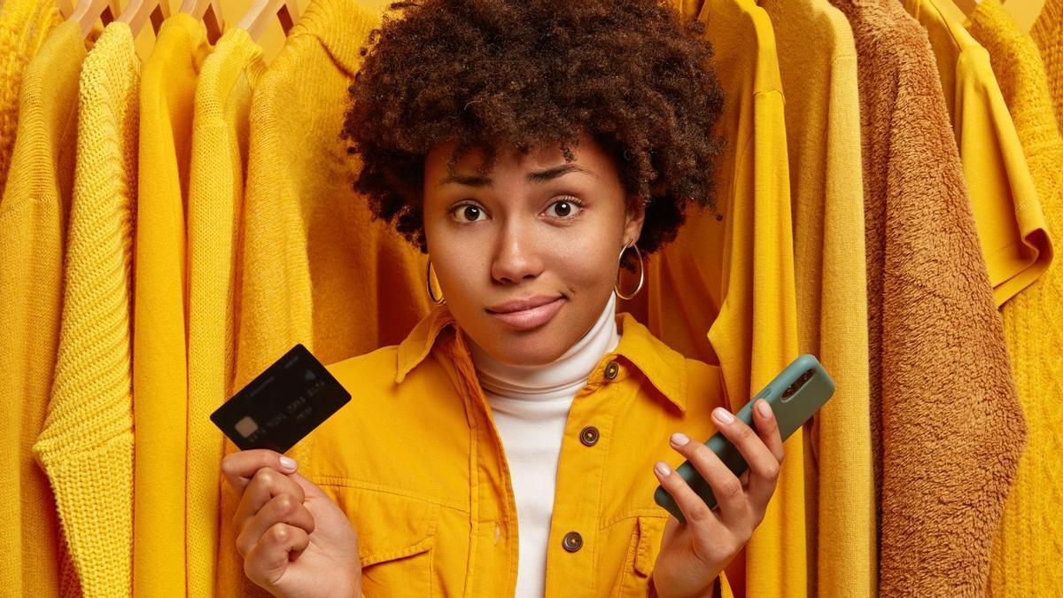 Una joven con cara de duda tras hacer una compra a través del móvil.