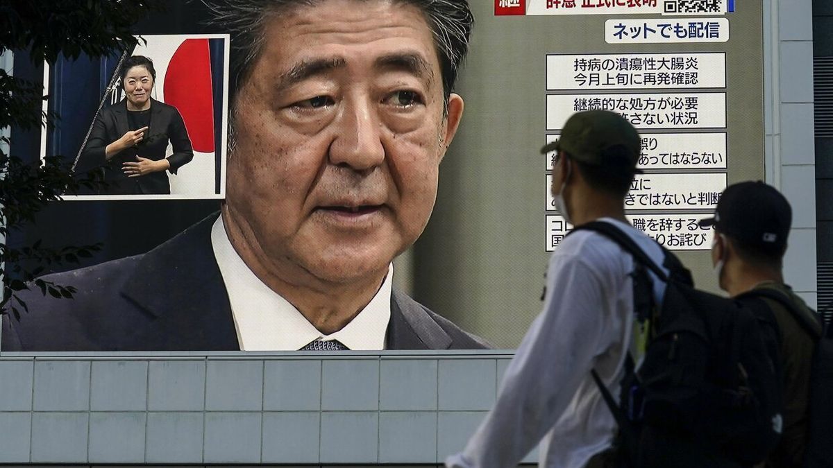 Dos hombres observan la noticia del ataque a Shinzo Abe en una pantalla gigante.