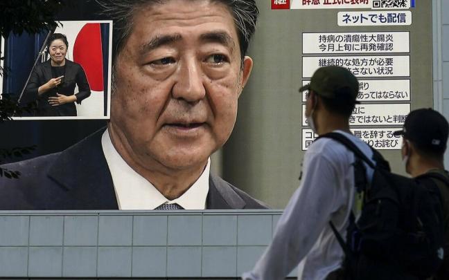 Dos hombres observan la noticia del ataque a Shinzo Abe en una pantalla gigante.