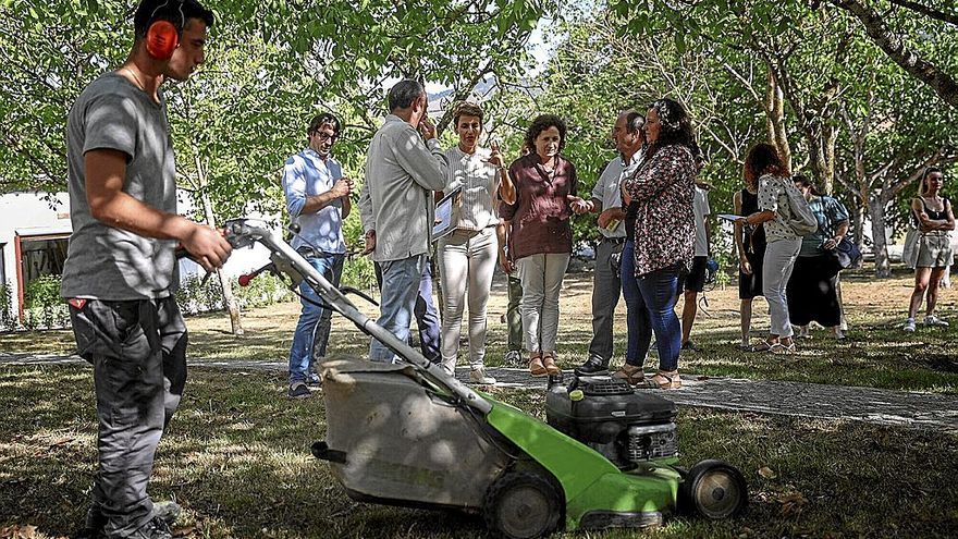 La presidenta Chivite y la consejera Maeztu visitan el centro, mientras un alumno de la escuela de jardinería usa una máquina cortacésped.