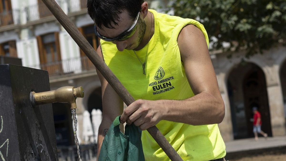 Un trabajador de la limpieza remoja su gorra en una fuente de la Plaza del Castillo en un día caluroso.