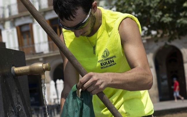 Un trabajador de la limpieza remoja su gorra en una fuente de la Plaza del Castillo en un día caluroso.