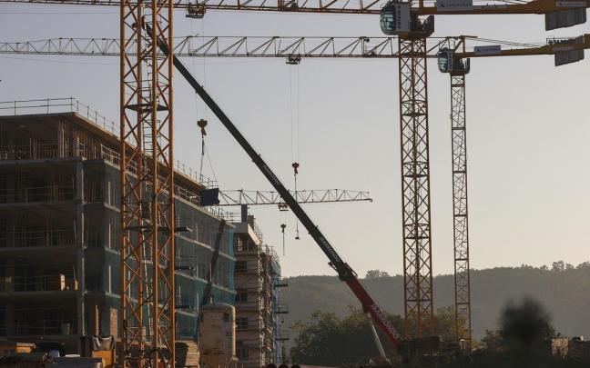 Varias grúas se alzan sobre un edificio de viviendas en construcción. Varias grúas se alzan sobre un edificio de viviendas en construcción.
