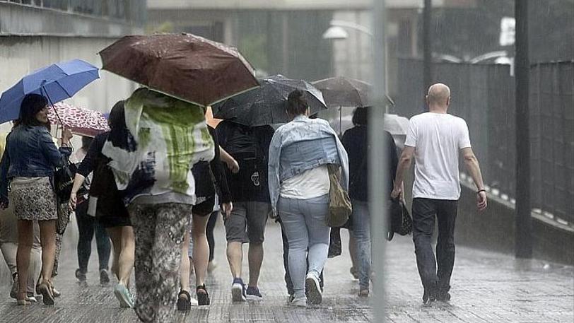 Varias personas con paraguas se protegen de la lluvia y el granizo en Euskadi.