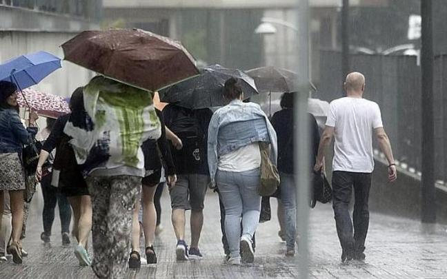 Varias personas con paraguas se protegen de la lluvia y el granizo en Euskadi.