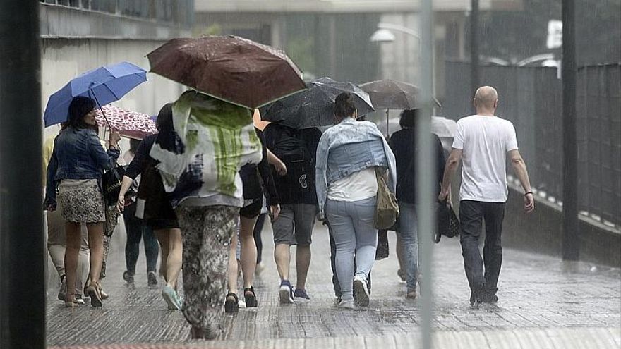 Varias personas con paraguas se protegen de la lluvia y el granizo en Euskadi.