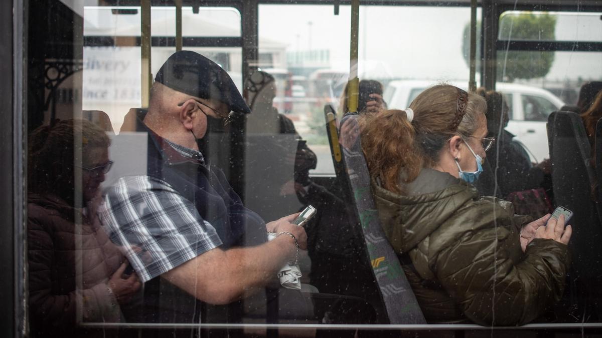Viajeros con mascarilla en un autobús.