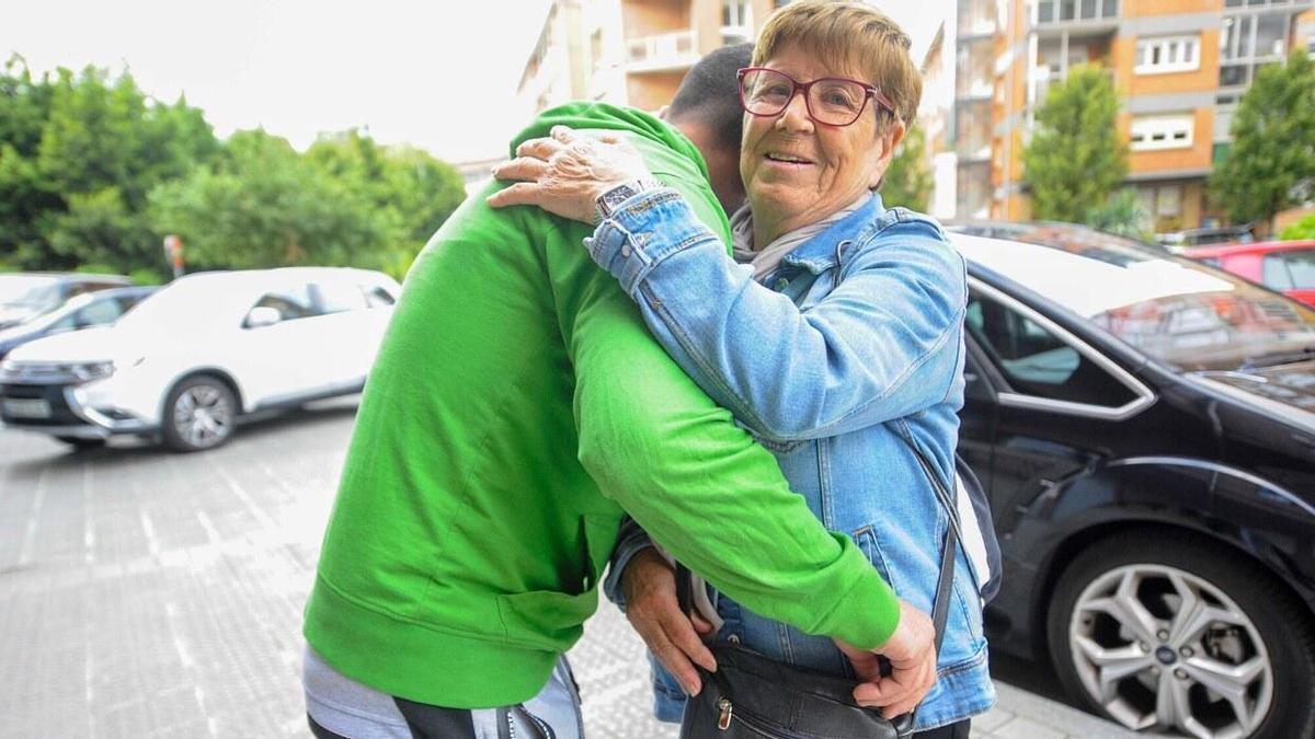 Una mujer recibe el abrazo de un joven en la vía pública.