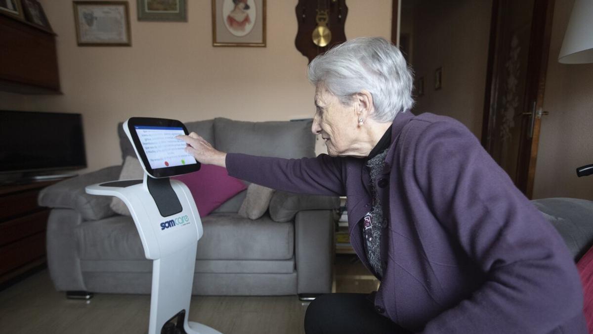 María Teresa Echalecu con su robot asistencial en su piso, facilitado por el Ayuntamiento de Barcelona