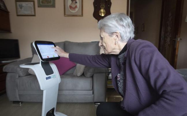 María Teresa Echalecu con su robot asistencial en su piso, facilitado por el Ayuntamiento de Barcelona