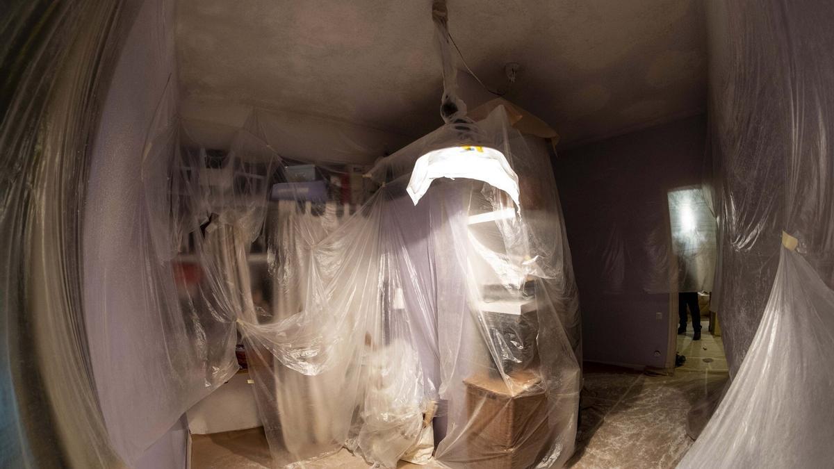 Enseres familiares, amontonados y cubiertos para protegerlos de los trabajos de pintura.