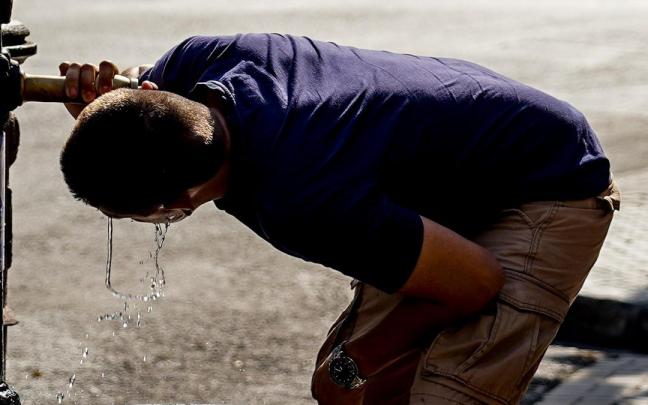 Un joven bebe de una fuente para mitigar el calor.