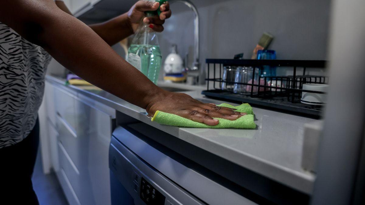 Una empleada del hogar limpia la encimera de la cocina.