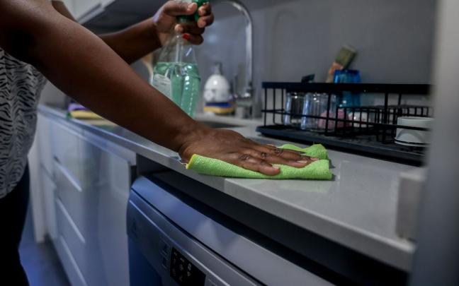 Una empleada del hogar limpia la encimera de la cocina. Una empleada del hogar limpia la encimera de la cocina.
