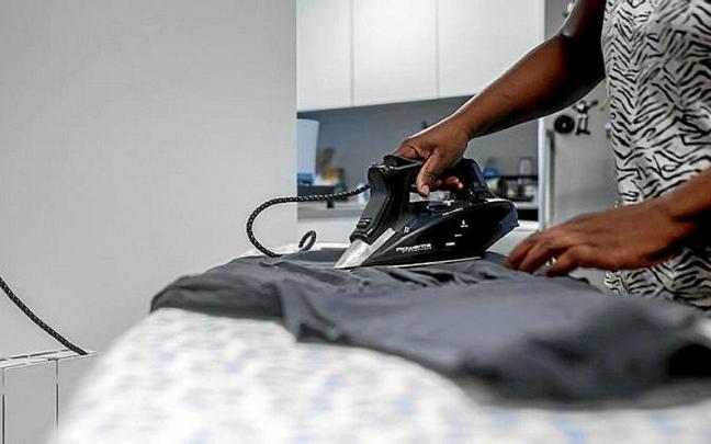 Una trabajadora del hogar plancha una camiseta.
