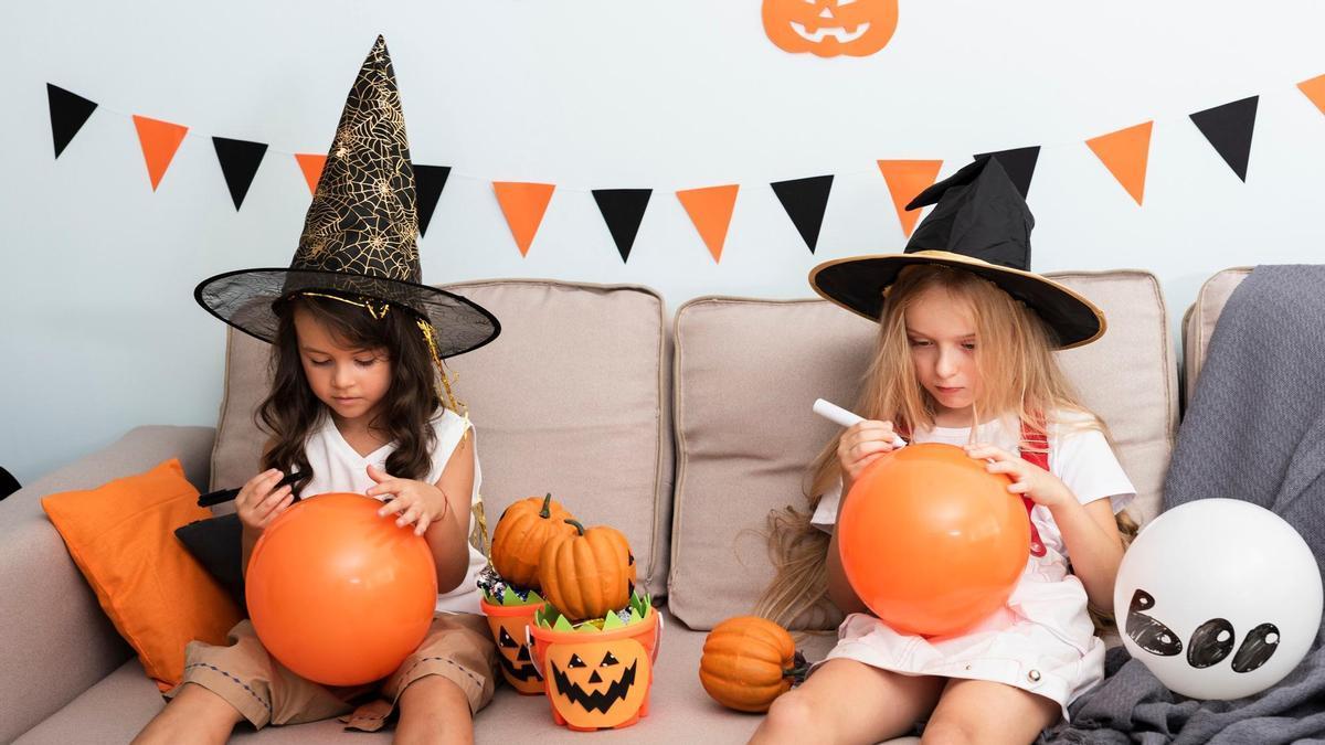 Dos niñas pintan globos para decorar la casa por Halloween.