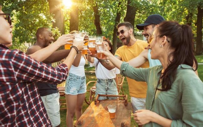 Chicos y chicas beben durante una barbacoa en el campo.