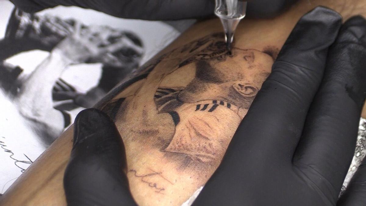 Una persona se hace un tatuaje de Lionel Messi besando la Copa del Mundo.