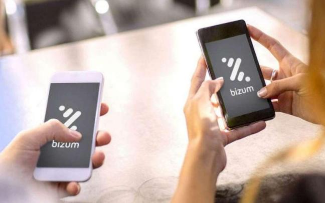 Dos personas realizan una transferencia con Bizum. Dos personas realizan una transferencia con Bizum.