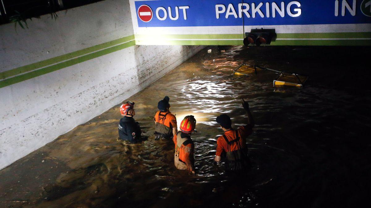 Los bomberos buscan supervivientes en el parking inundado.
